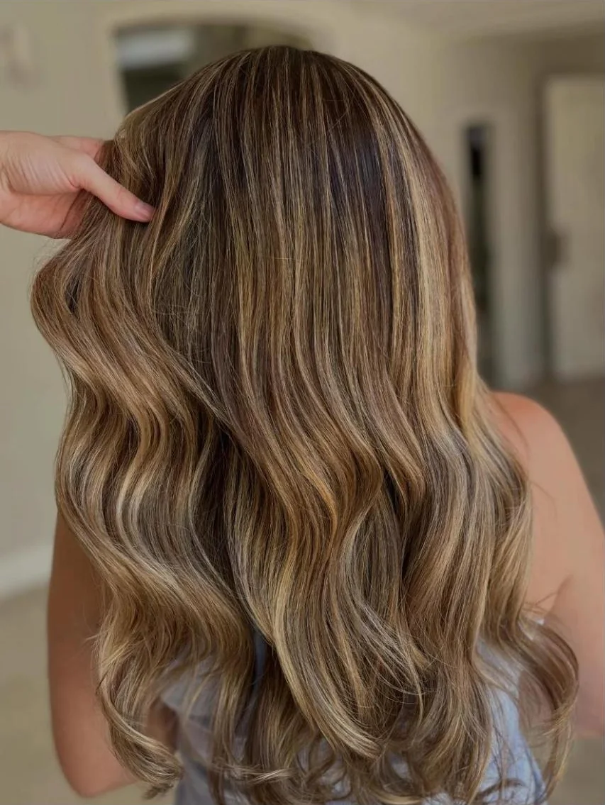 Cabelo longo com mechas loiras e ondas, visto de costas